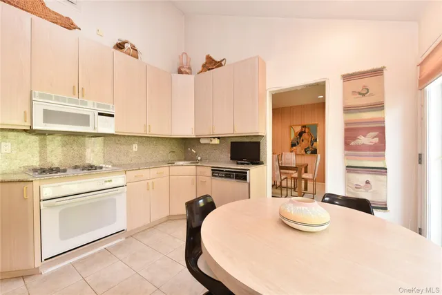 a kitchen with stainless steel appliances kitchen island granite countertop a sink a stove a table and chairs