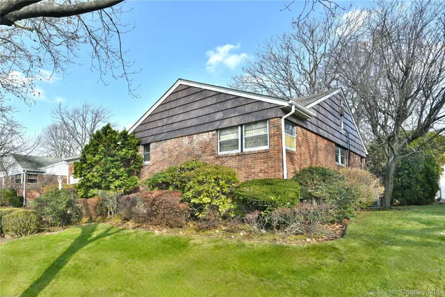 a backyard of a house with plants and large tree