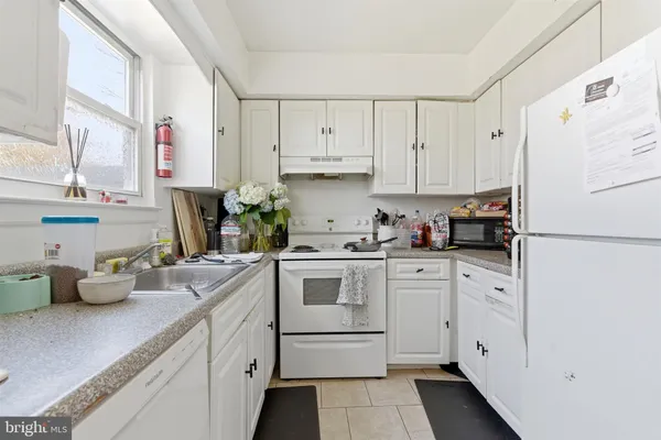 a kitchen with white cabinets and white appliances