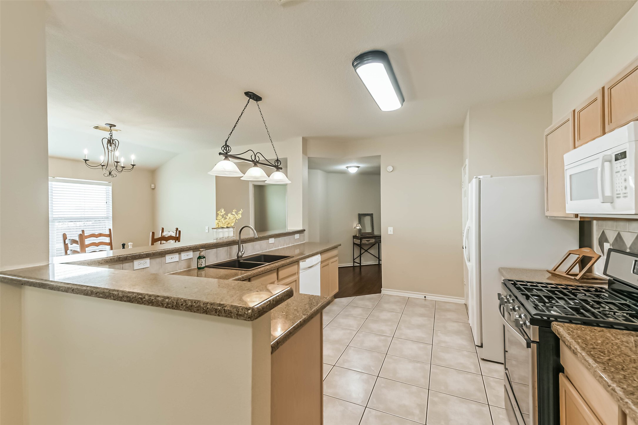 18239 Trinity Knoll Way Humble, TX 77346 - Photo 13 of 38 a kitchen with kitchen island granite countertop a stove a sink a counter top space and cabinets