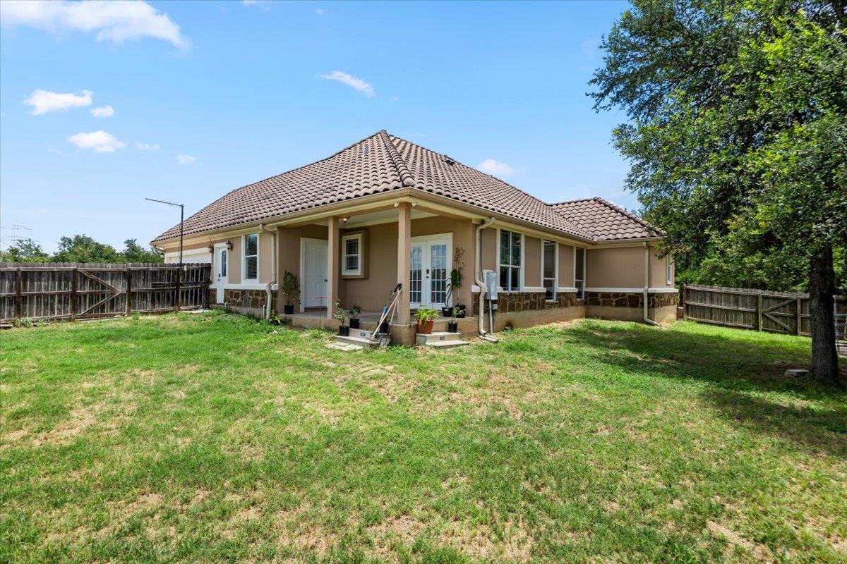 437 Balch Road Elgin, TX 78621 - Photo 25 of 37 A well-maintained yard embraces this charming residence, framed by mature trees and sturdy fencing.