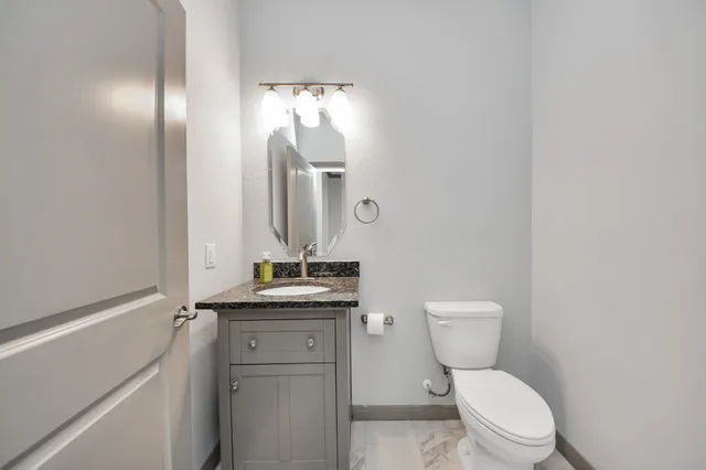 a bathroom with a granite countertop toilet sink and mirror