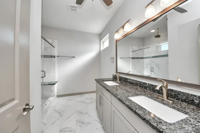 a bathroom with a granite countertop sink a mirror and shower