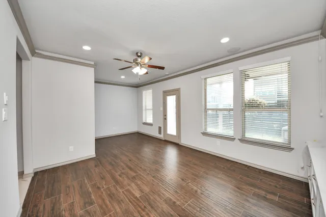 a view of an empty room with a window and wooden floor