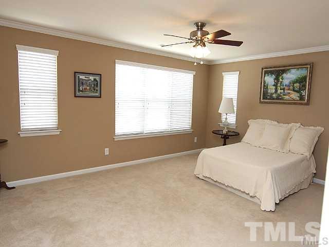 9826 Grettle Court Raleigh, NC 27617 - Photo 5 of 9 a bedroom with a bed and a chandelier