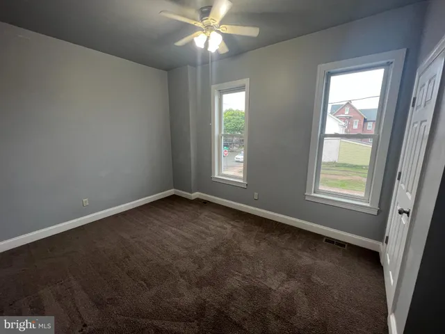 an empty room with windows and fan