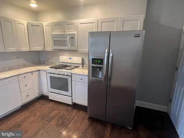 a kitchen with cabinets stainless steel appliances and wooden floor