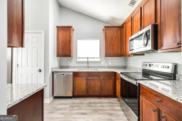 a kitchen with stainless steel appliances granite countertop a sink stove and cabinets