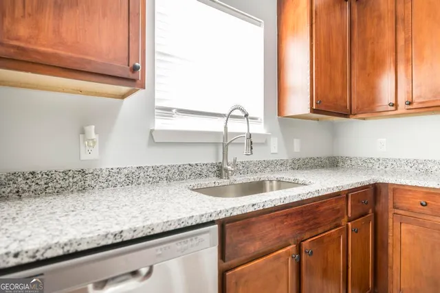 a kitchen with granite countertop a sink and a white cabinets