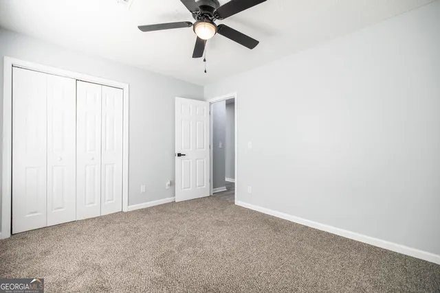 an empty room with closet and a chandelier fan