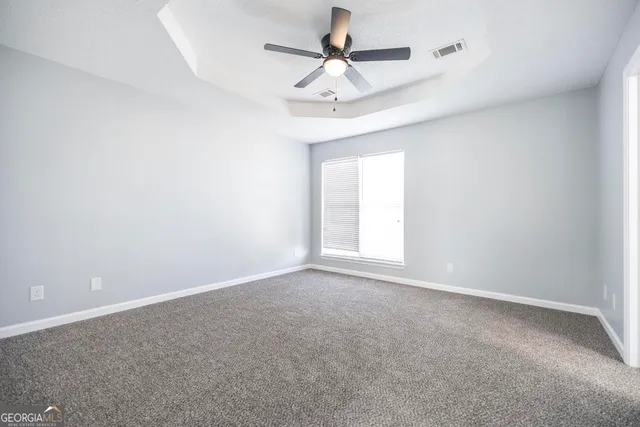 an empty room with a chandelier fan and windows