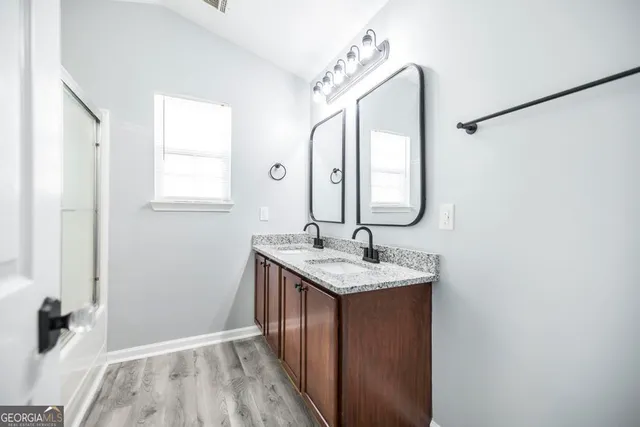 a en suite bathroom with a granite countertop sink and a mirror