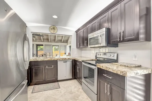 a kitchen with stainless steel appliances granite countertop a stove sink microwave and refrigerator