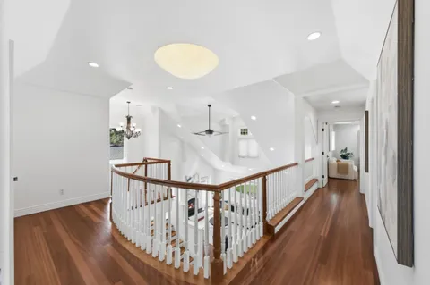 a view of a hallway with wooden floor and staircase