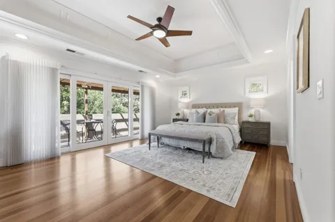 a bedroom with a large bed and a large window with wooden floor