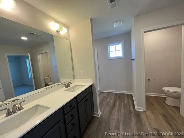 a spacious bathroom with a double vanity sink a toilet and a mirror