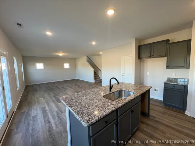 a kitchen with granite countertop kitchen island stainless steel appliances a sink stove and refrigerator