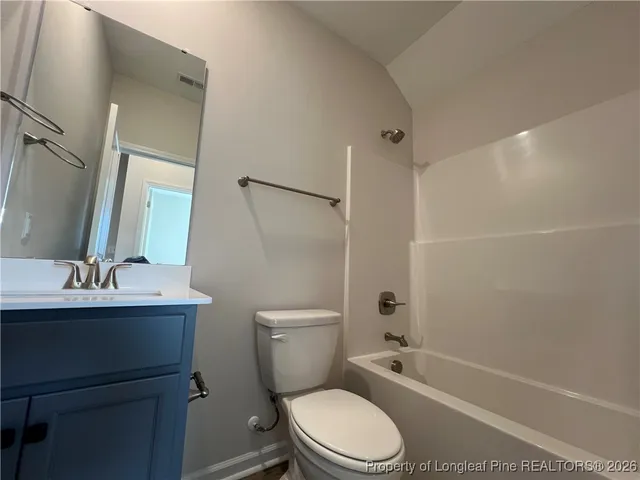 a bathroom with a toilet a sink a mirror a bathtub and vanity
