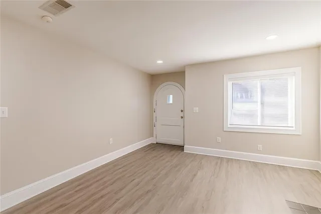 an empty room with wooden floor and windows