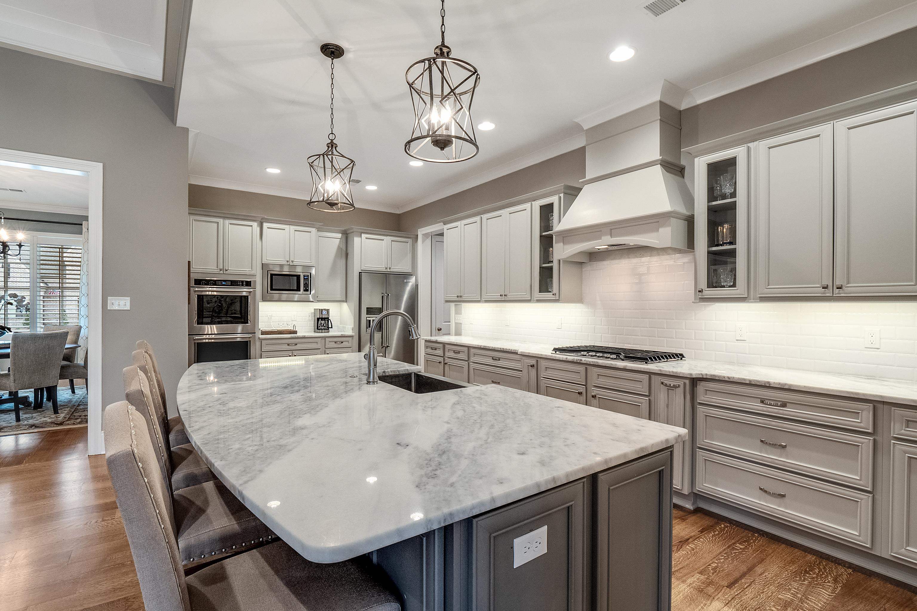 47 Addiegreen Cove Collierville, TN 38017 - Photo 8 of 34 a kitchen with granite countertop a stove a sink a dining table and chairs with wooden floor