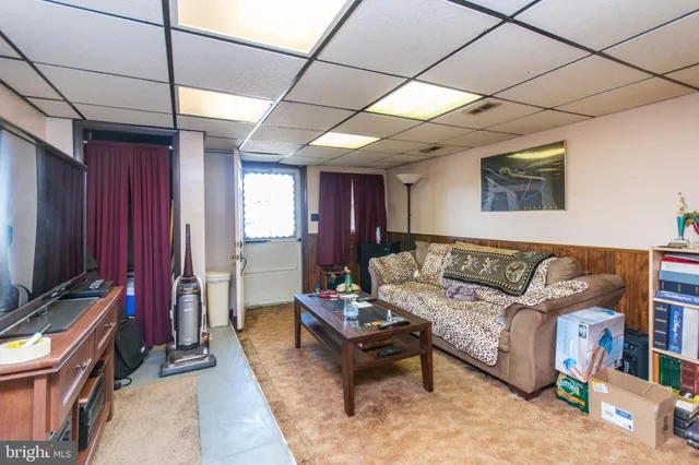 a living room with furniture a flat screen tv and a refrigerator
