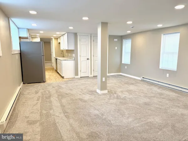 a view of an empty room with kitchen and window