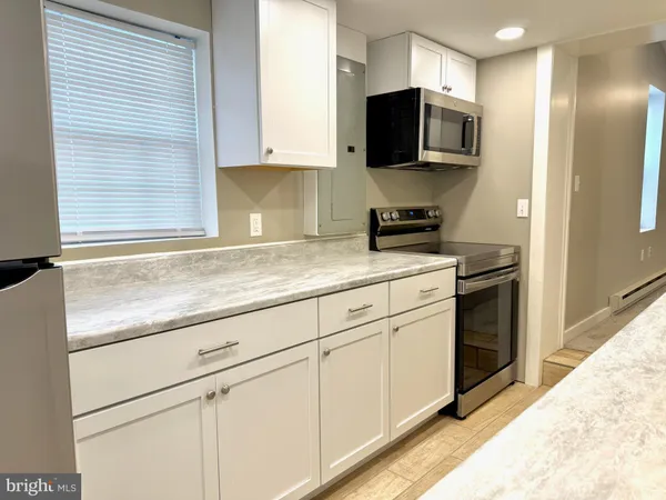 a kitchen with granite countertop white cabinets and stainless steel appliances
