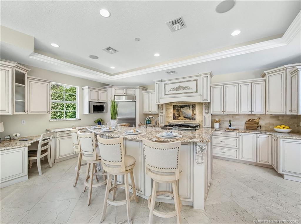 6 West High Point Road Stuart, FL 34996 - Photo 9 of 54 a kitchen with stainless steel appliances granite countertop a stove top oven a sink dishwasher a dining table and chairs with wooden floor