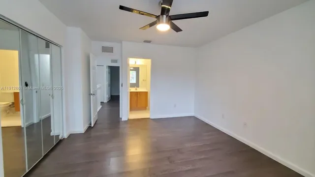 an empty room with wooden floor closet and windows