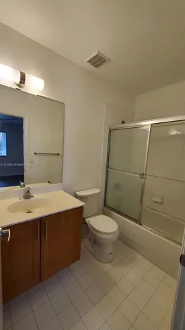 a view of a hallway with wooden floor and a bathroom