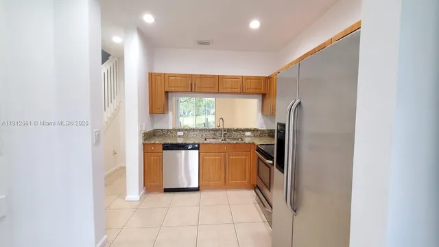 a kitchen with stainless steel appliances granite countertop a refrigerator stove and sink