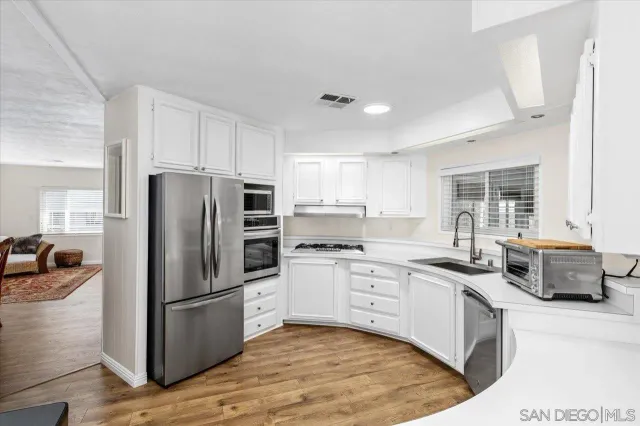 a kitchen with stainless steel appliances granite countertop a stove refrigerator sink and dishwasher with wooden floor