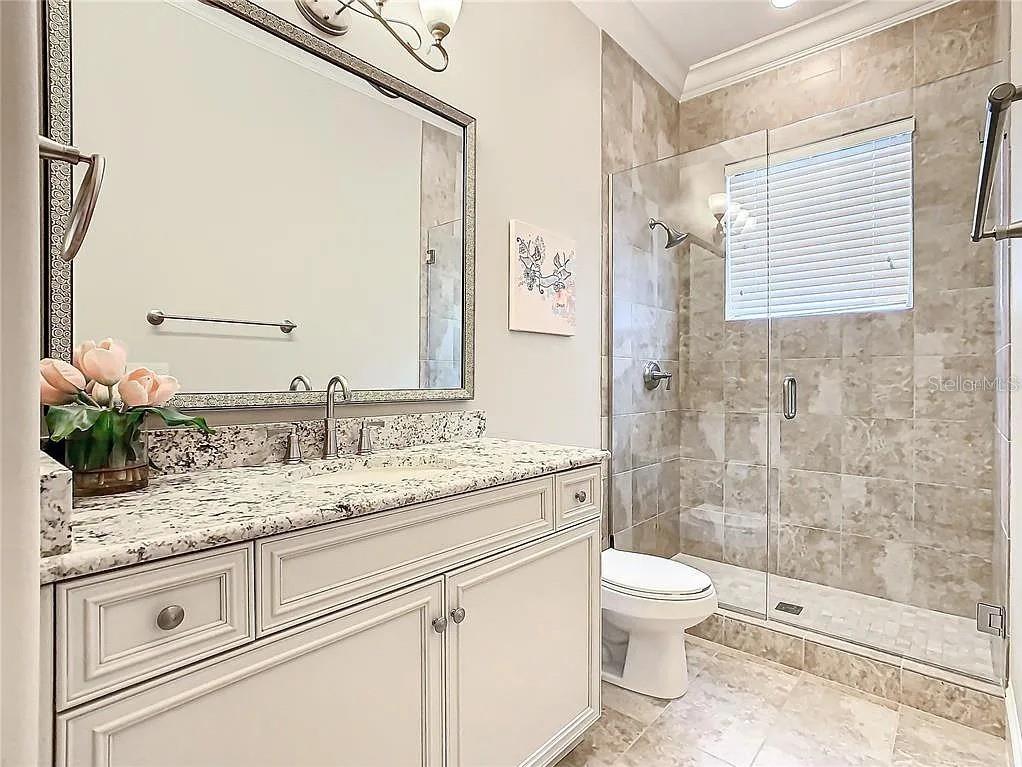 395 Muirfield Loop Reunion, FL 34747 - Photo 24 of 50 a bathroom with a granite countertop sink toilet a mirror and shower