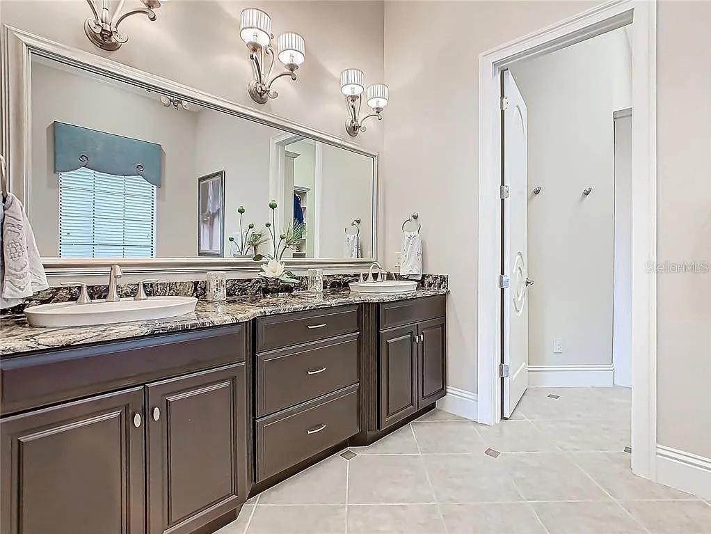 395 Muirfield Loop Reunion, FL 34747 - Photo 39 of 50 a spacious bathroom with a granite countertop sink and a mirror