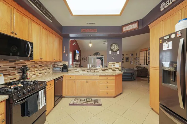 a kitchen with stainless steel appliances granite countertop a stove a sink and a refrigerator