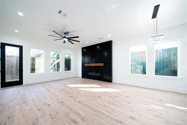 a view of an empty room with a window and wooden floor