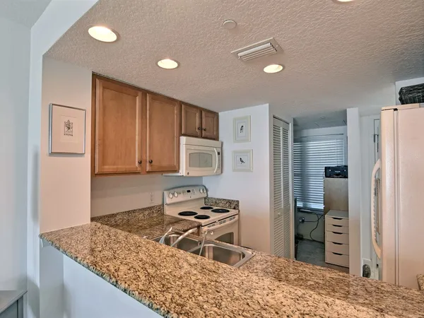 a kitchen with stainless steel appliances granite countertop a refrigerator a stove and a sink