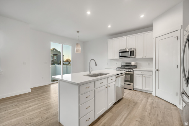1058 Lilac Way Mapleton, UT 84664 - Photo 5 of 28 Kitchen with pendant lighting, a center island with sink, stainless steel appliances, white cabinetry, and light wood finished floors
