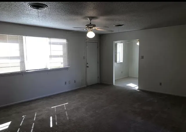 an empty room with windows and fan