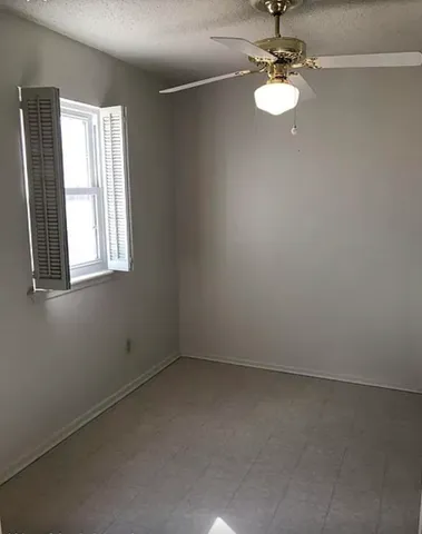 an empty room with windows and fan