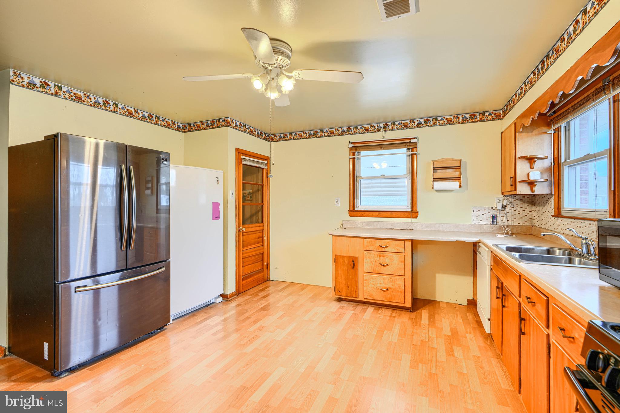 3118 Lynch Road Sparrows Point, MD 21219 - Photo 26 of 46 a kitchen with stainless steel appliances granite countertop a refrigerator a sink dishwasher a stove and a dining table with wooden floor