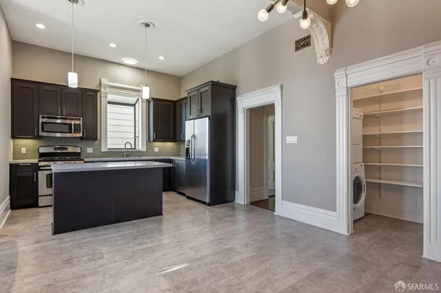 a large kitchen with a large counter top stainless steel appliances and cabinets