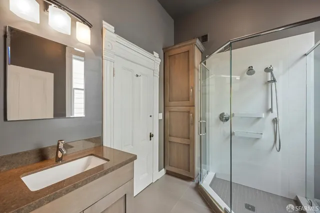a bathroom with a tub sink vanity granite and shower