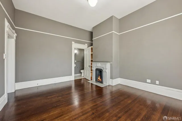 a view of empty room with wooden floor and fireplace
