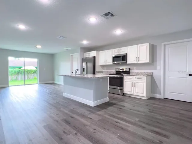 a kitchen with stainless steel appliances granite countertop a stove a sink and a microwave