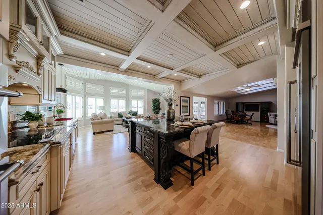 a view of a kitchen with kitchen island granite countertop wooden floors and a black stainless steel appliances