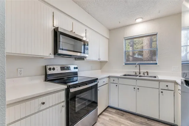 a kitchen with white cabinets appliances a sink and a window