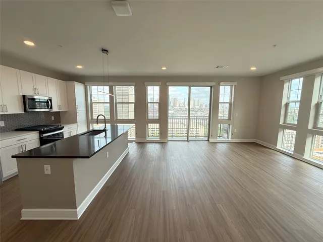 a large living room with stainless steel appliances wooden floors and large window