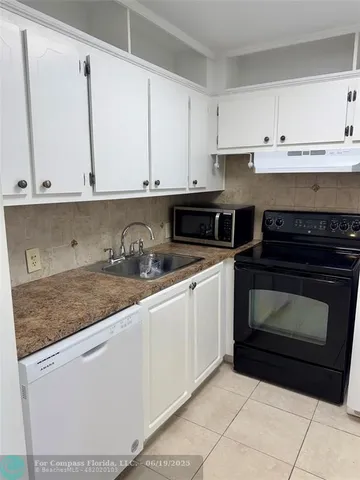 a kitchen with granite countertop white cabinets and sink