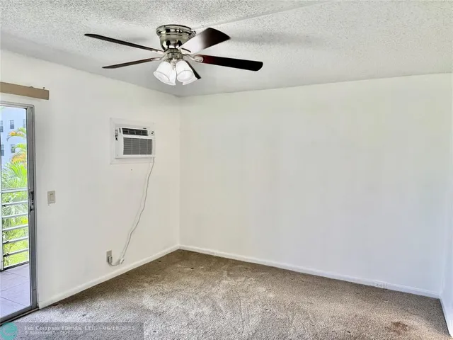 an empty room with a chandelier fan and windows